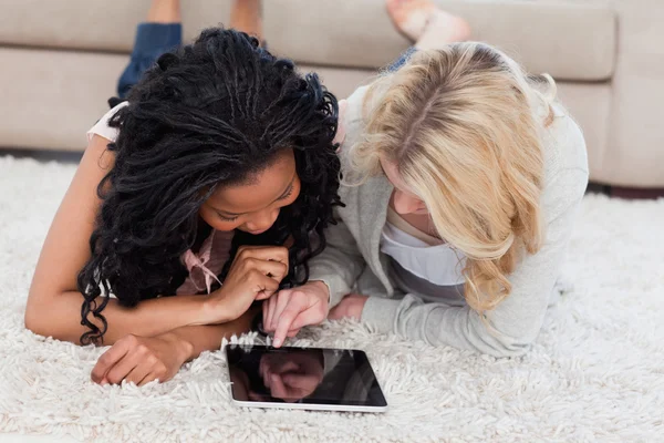 Une femme est couchée sur le sol à l'aide d'un ordinateur tablette tandis que son — Photo