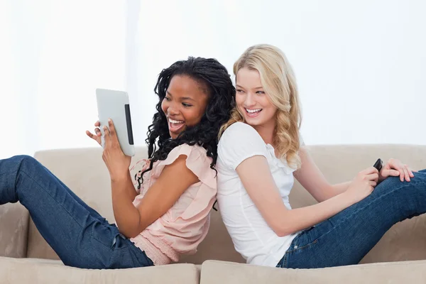 A woman leaning up against her friends back is holding a tablet — Stock Photo, Image