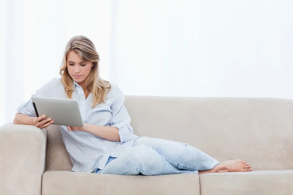 一个女人坐在沙发上使用平板电脑 — 图库照片