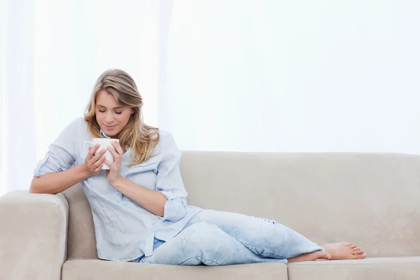 A woman is smelling a cup of coffee that she is holding — Stock Photo, Image