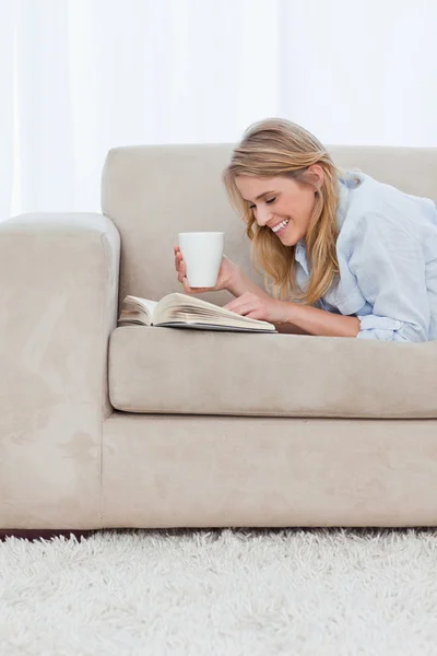 Eine Frau mit einer Tasse Kaffee liest ein Buch — Stockfoto