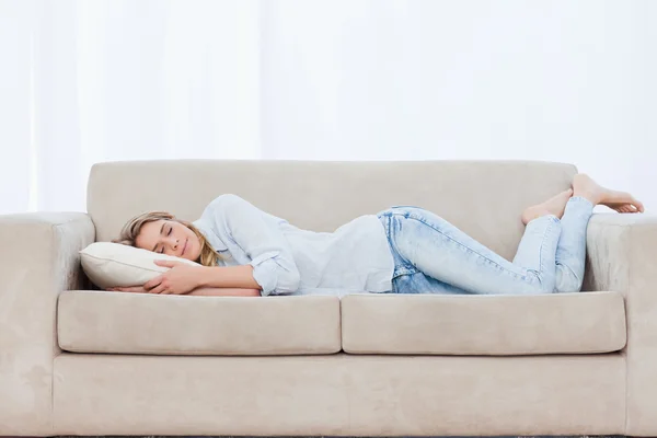 A woman is lying on a couch sleeping — Stock Photo, Image