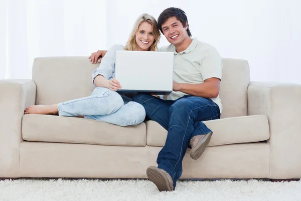 ノート パソコンと笑みを浮かべてカップルがカメラを見ています。 — ストック写真