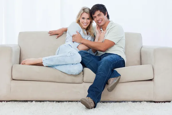 Um casal sentado em um sofá abraçando um ao outro — Fotografia de Stock