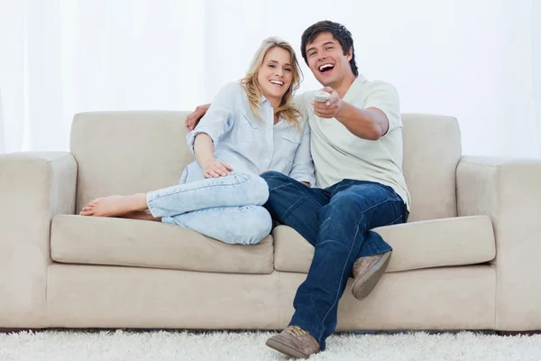 Una joven pareja está sentada mirando a la cámara y riéndose — Foto de Stock
