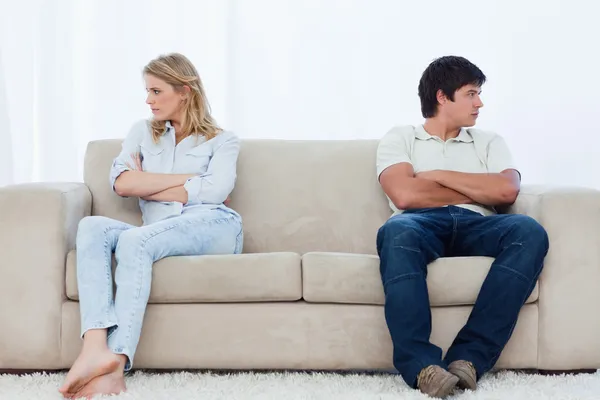 Ein Paar sitzt mit verschränkten Armen an den beiden Enden der Couch — Stockfoto