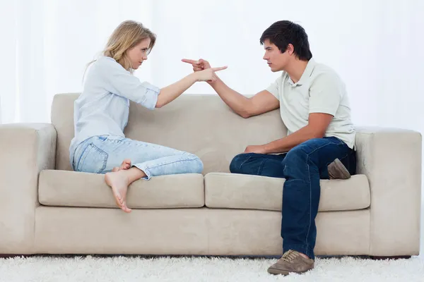 Un couple assis sur un canapé se pointe du doigt — Photo