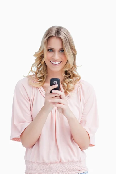 Žena držící mobilní telefon se dívá na kameru — Stock fotografie