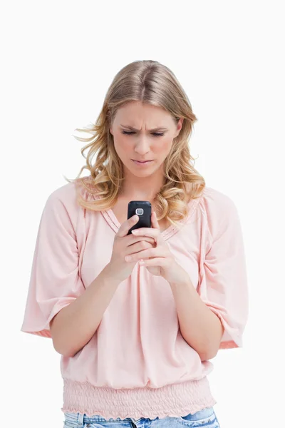 Uma mulher com uma expressão séria está olhando para seu telefone celular — Fotografia de Stock