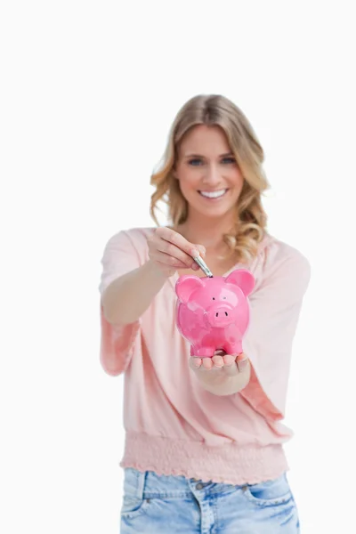 Mulher segurando um banco porquinho está colocando dinheiro nele — Fotografia de Stock