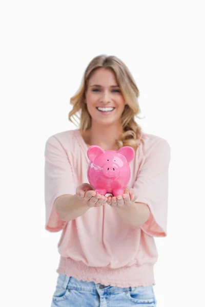 Een lachende vrouw houdt een piggy bank in de Palm van haar hand — Stockfoto