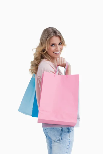 Una mujer que lleva bolsas de compras sonríe a la cámara —  Fotos de Stock