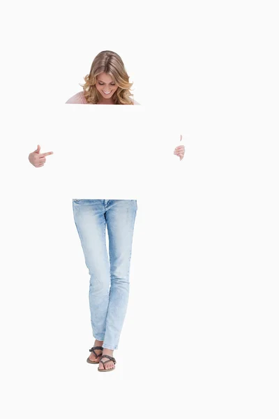 Женщина смотрит вниз на плакат, который она держит — стоковое фото