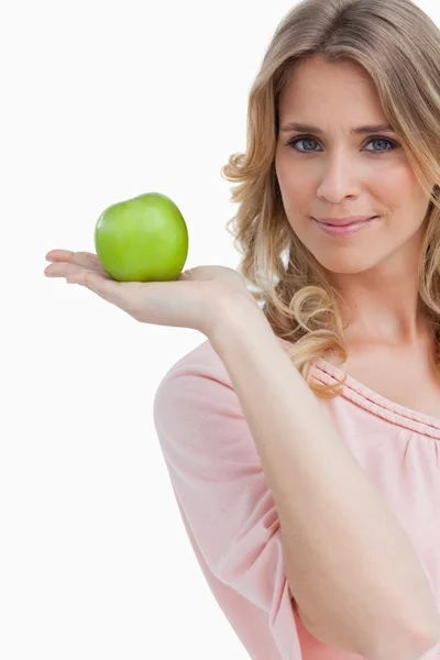 Kameraya bakarak bir yeşil elma tutan genç kadın — Stok fotoğraf
