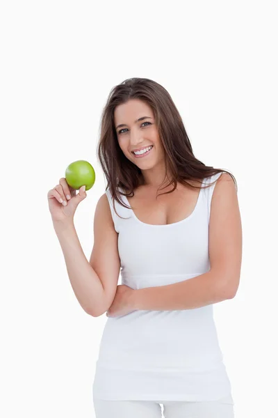 Mujer morena sonriente sosteniendo una manzana verde — Foto de Stock