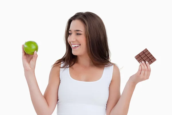 Улыбающаяся молодая женщина смотрит на зеленое яблоко — стоковое фото