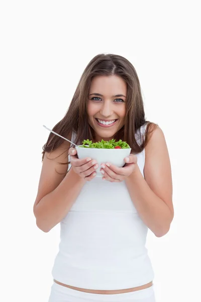 Smiling young woman looking at the camera while holding a bowl o — Stock Photo, Image