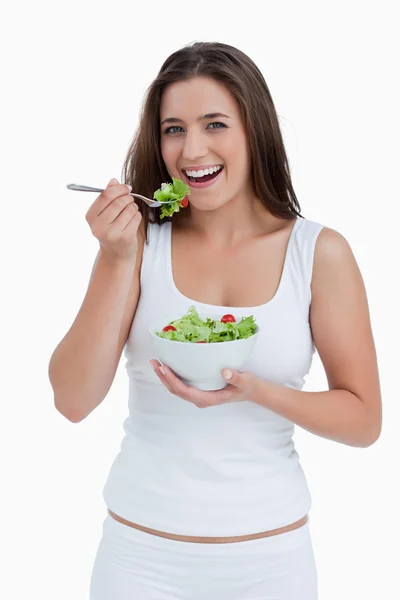 Χαμογελώντας νεαρή γυναίκα τρώει μια σαλάτα — Φωτογραφία Αρχείου