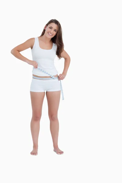 Sorrindo mulher morena medindo sua cintura — Fotografia de Stock