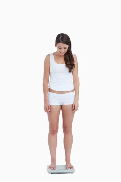 Mujer joven mirando sus pesas — Foto de Stock