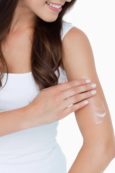 stock image Smiling brunette applying some cream on her arm