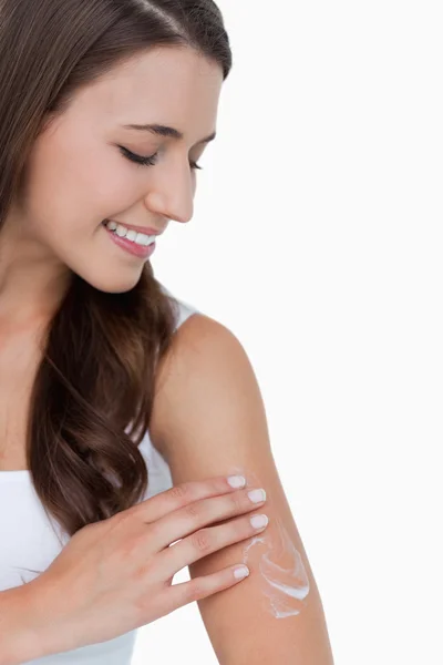 Peaceful brunette applying some cream on her arm — Stock Photo, Image
