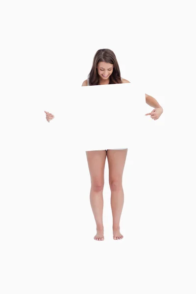 Mulher morena apontando um cartaz em branco — Fotografia de Stock