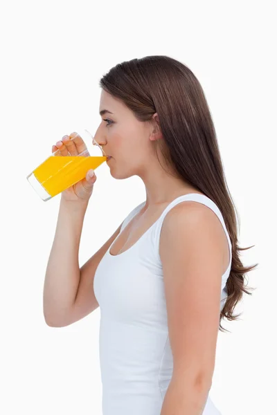 Sidovy av en attraktiv brunett dricka en apelsinjuice — Stockfoto