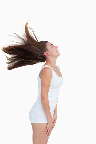 Вид сбоку на молодую женщину, стоящую и переворачивающую волосы — стоковое фото