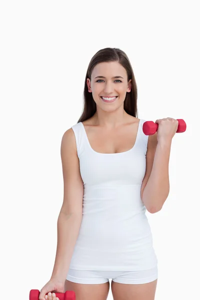 Attractive brunette holding red dumbbells — Stock Photo, Image