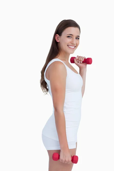 Vista lateral de una mujer sonriente sosteniendo pesas — Foto de Stock