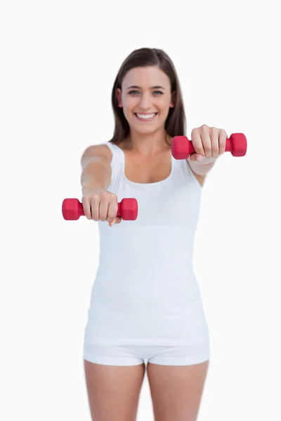 Röda vikter som hålls av en ung brunett — Stockfoto