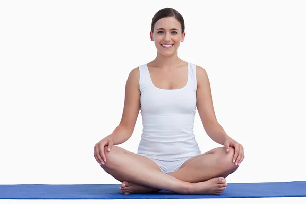 Sonriente a joven meditando sobre una estera de yoga — Stok fotoğraf