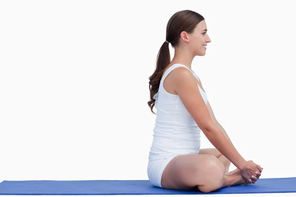 Brünette Frau sitzt auf einer Yogamatte — Stockfoto