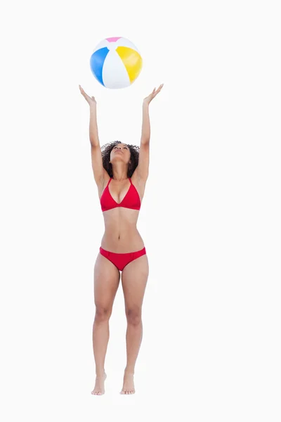 Atractiva mujer en bikini lanzando una pelota de playa — Foto de Stock