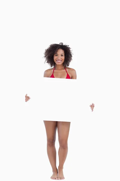 Mulher sorridente de biquíni segurando um cartaz em branco — Fotografia de Stock