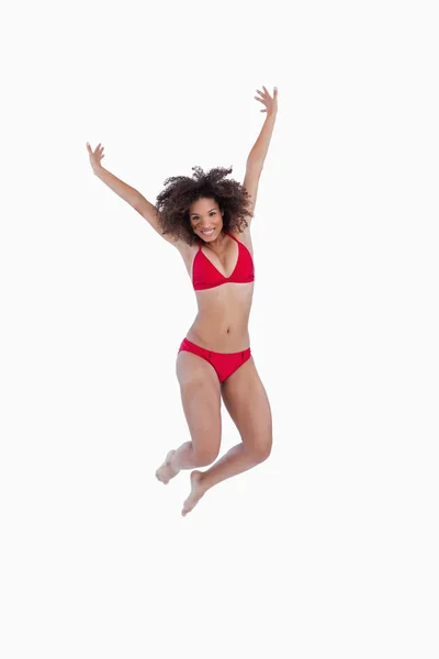 Happy brunette woman jumping while raising her arms — Stock Photo, Image