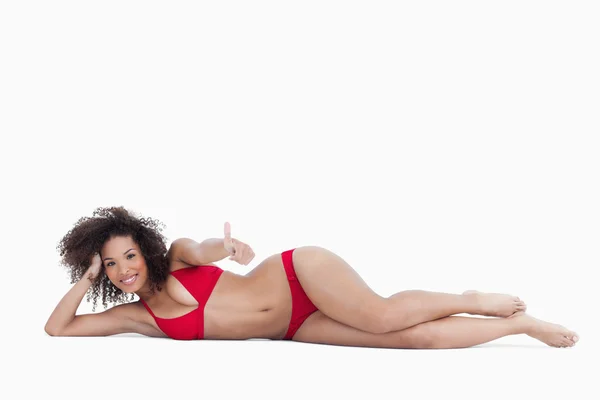 Smiling woman lying down while placing her thumbs up — Stock Photo, Image