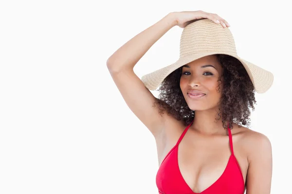 Приваблива брюнетка в купальнику тримає її солом'яний капелюх — стокове фото