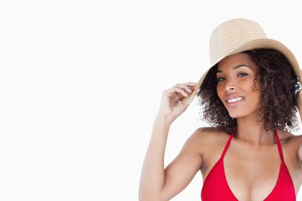Smiling woman looking at the camera while holding her straw hat — Stock Photo, Image