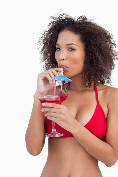 Young woman sipping a cocktail while looking at the camera — Stock Photo, Image