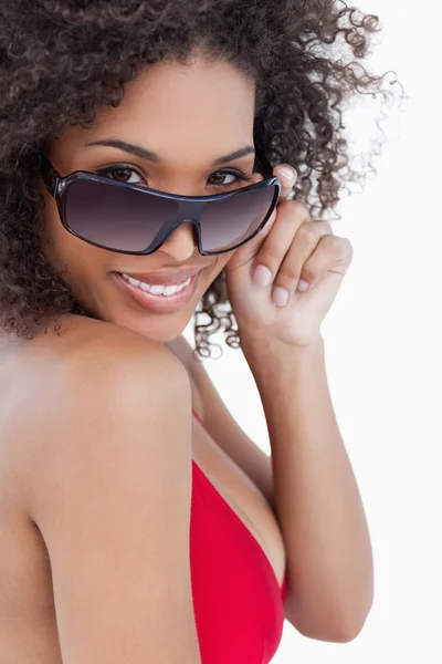 Улыбающаяся женщина смотрит на свои солнечные очки — стоковое фото
