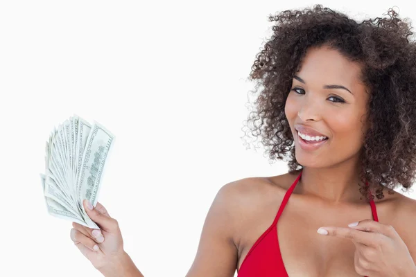 Lächelnde Frau zeigt auf einen Fan von Geldscheinen — Stockfoto