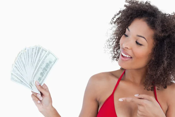 Sorrindo morena mulher apontando um fã de notas de dólar — Fotografia de Stock