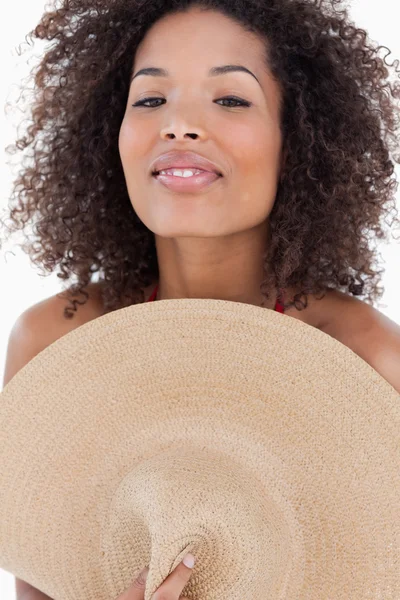 Attractive brunette woman hiding her body behind a hat — Stock Photo, Image