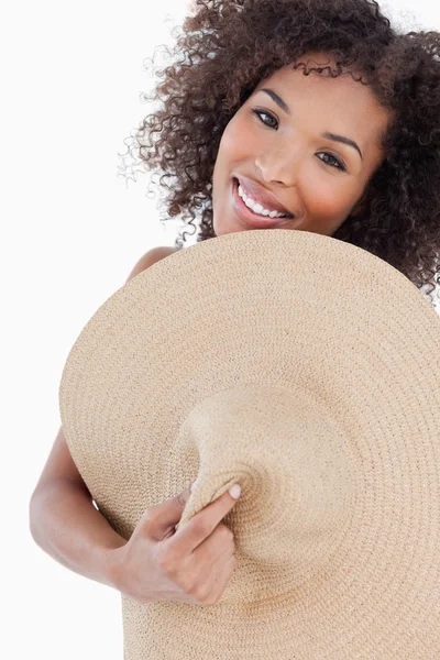 Young woman hiding her body behind a straw hat — Stockfoto