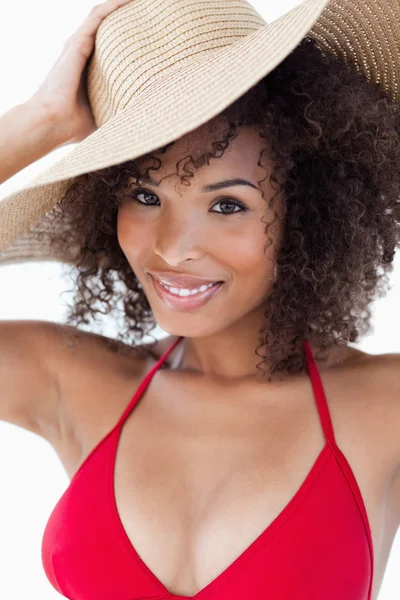Mujer sonriente mirando a la cámara mientras sostiene su sombrero — Foto de Stock