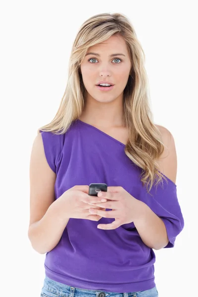 Verrast blonde vrouw die houdt van haar mobiele telefoon — Stockfoto
