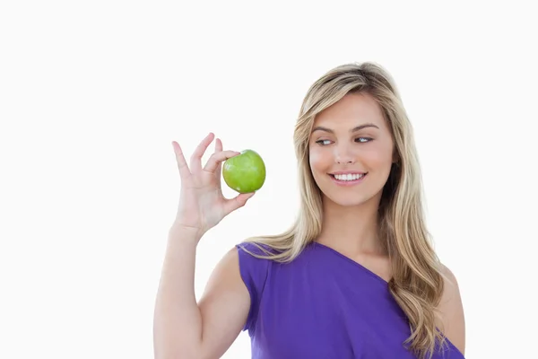 Glückliche junge blonde Frau beim Anblick eines grünen Apfels — Stockfoto
