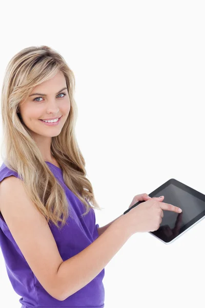 Glückliche blonde Frau schaut in die Kamera, während sie ihr Tablet benutzt — Stockfoto